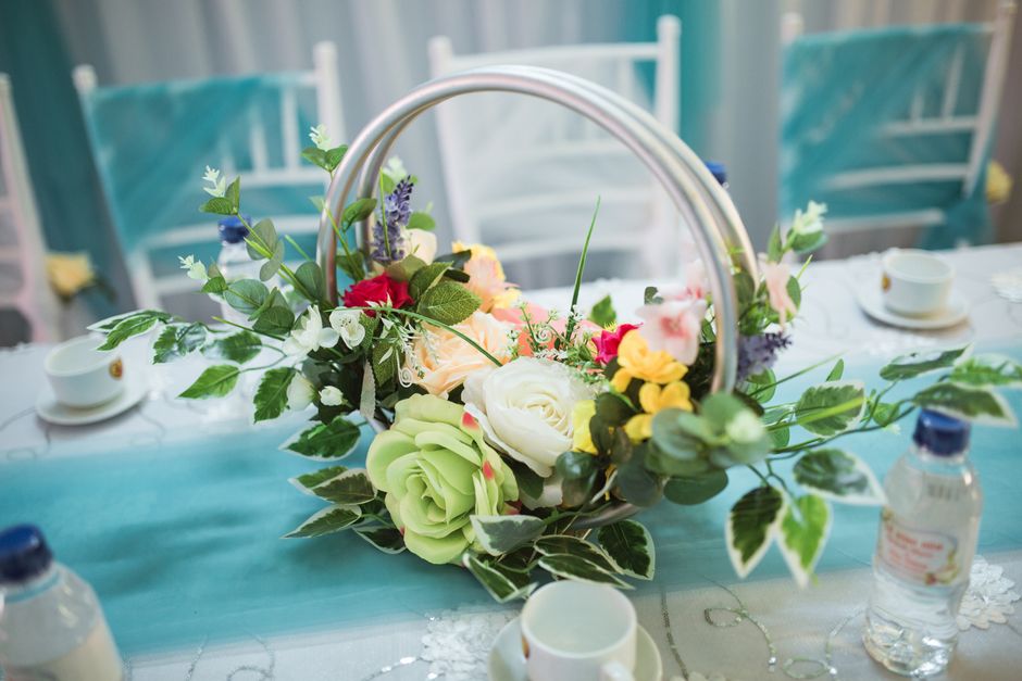 A floral arrangement featuring a mix of fresh flowers, including white roses, pale green succulents, pink and red blooms, and sprigs of lavender, all artistically arranged with various green foliage a