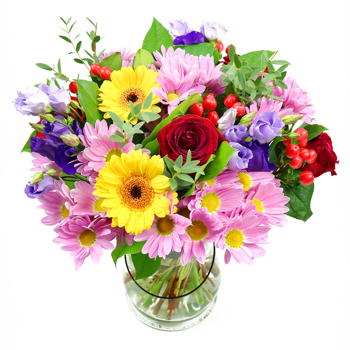 In this image, a lush, mixed-colour bouquet fills a clear glass vase, creating a vivid focal point against a plain white background that recalls the calm light of a Palmers Green studio. The arrangement is generously rounded and full, with every space thoughtfully layered. Deep red roses, rich and velvety, form the emotional core, their tightly curled petals suggesting classic affection and care. Just beside them, two bright yellow gerbera daisies with dark golden-brown centres bring a jolt of happiness, like little bursts of sunshine that might echo a bright morning walk through Broomfield Park. Soft pink and lavender daisies or chrysanthemums spread outwards, each bloom a cluster of fine, delicate petals surrounding a tiny yellow heart, giving the bouquet a soothing, airy halo. Interspersed throughout, slender stems of purple and lilac lisianthus add height and movement, their bell-shaped flowers gently unfurling, lending a quiet sophistication. Small clusters of round, glossy red hypericum berries pop up between the petals, catching the light and adding playful texture. A tapestry of green foliage, from broad, dark leaves to lighter, more feathery sprigs, flows through the design, framing the brighter flowers and reinforcing the sense of freshness. Through the transparent vase, you can see the stems carefully spiralled in clear water, a detail that shows the experienced hand of a local florist used to preparing bouquets for same-day delivery across Palmers Green, Winchmore Hill, and nearby streets. The whole composition feels like a joyful, yet considered, celebration piece - ideal for birthdays, congratulations, or simply bringing a burst of colour into a North London home.