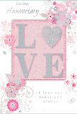 This anniversary card appears like a delicate floral artwork, as if a florist in Palmers Green translated a romantic bouquet into ink, glitter, and soft colour. In the centre, the word LOVE is spelled out in bold, raised letters that rise from the card in a blush pink tone. Each letter is edged with fine, iridescent glitter, creating a sparkling, tactile surface that catches the light with every slight movement, similar to how petals gleam under the soft glow of evening lights near Broomfield Park. The background is a gentle wash of pastel pink, soothing and warm, providing a serene stage for the central motif. Around the word, an airy arrangement of stylised flowers and leaves is illustrated in fine lines of white and silver, their petals layered with subtle tonal shading that hints at depth and softness, like real blossoms freshly arranged for an anniversary delivery. Curving stems and swirling tendrils weave between the blooms, adding a sense of motion and grace, suggesting the natural rhythm of a hand-tied bouquet being turned and adjusted on a florist's bench. Tiny accents of silver foil glimmer discreetly, lending sophistication without overwhelming the design. Flowing script text, placed thoughtfully within the composition, expresses heartfelt anniversary wishes in an elegant, looping style that harmonises with the floral swirls. The entire card radiates a feeling of intimate celebration and lasting affection, perfectly suited to accompany fresh flowers sent to a home in Palmers Green, where each detail whispers of shared memories, quiet moments, and the gentle beauty of enduring love.